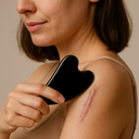 Female demonstrating gua sha massage technique on surgical scars with black stone